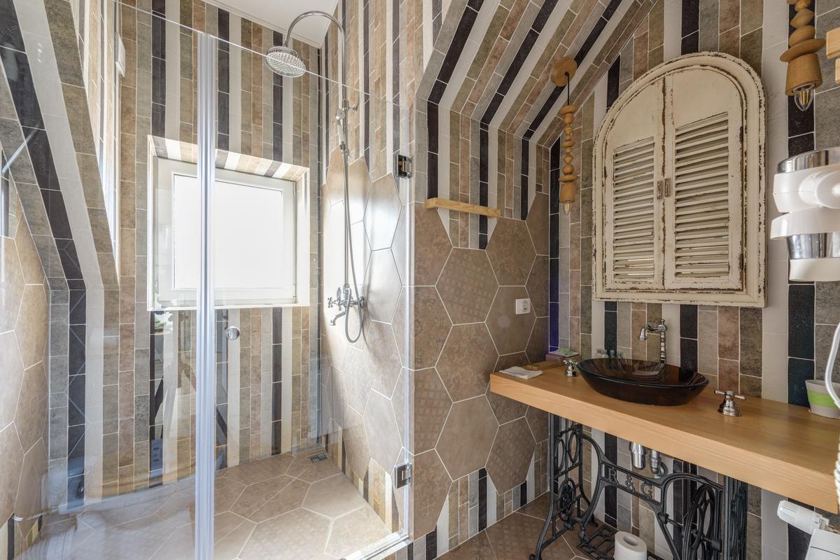 Tiled shower with a glass enclosure and patterned wall tile