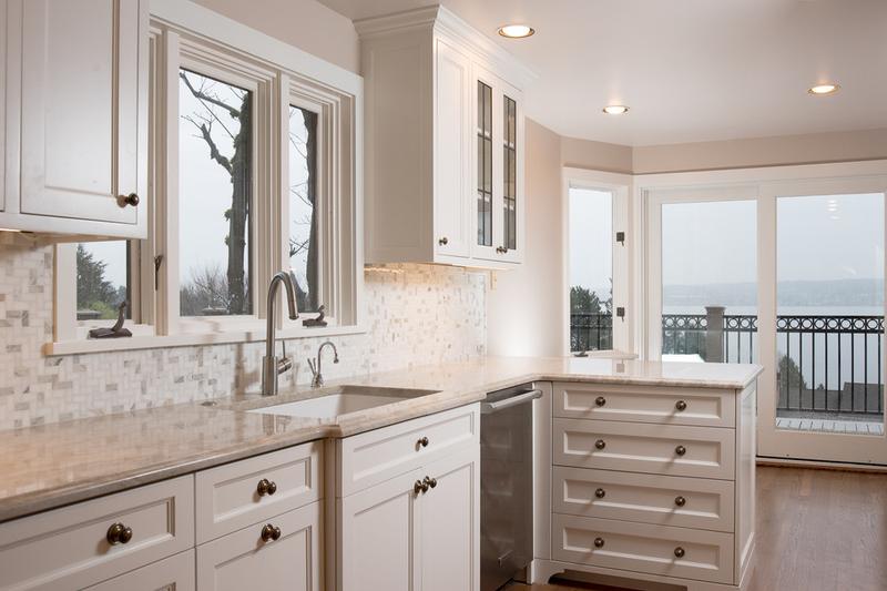 White kitchen with a mosaic tile backsplash and glass doors out to a balcony over the water