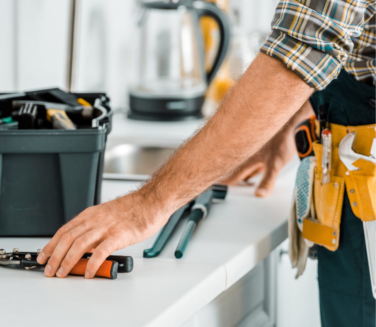 Worker wearing a tool belt reaching for tools on a counter
