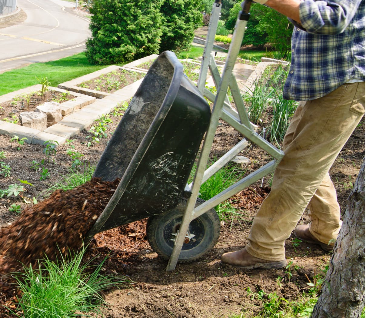 Man dumping soil out of a wheelbarrow into a residential garden bed