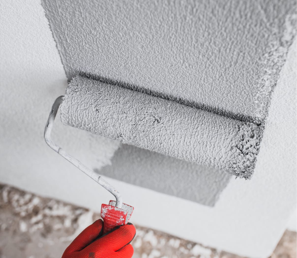 Worker using a roller to paint an interior wall