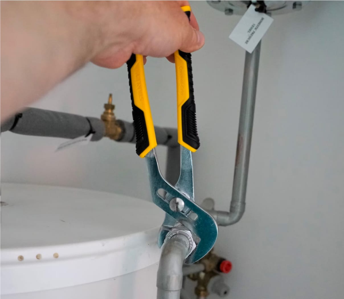 Hand holding a wrench tightening plumbing pipes
